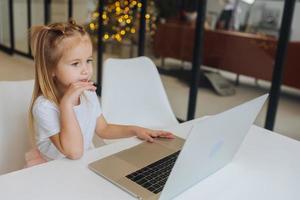 Little girl using tablet computer sitting at table photo