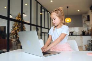 Little girl using tablet computer sitting at table photo