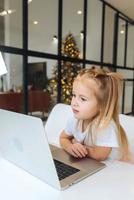 Little girl using tablet computer sitting at table photo