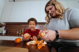 mamá e hija pelan mandarinas en la cocina foto