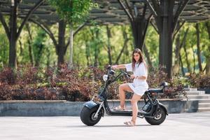 Young beautiful woman and an electric scooter, ecological transport photo