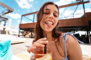 Pretty woman in bikini drinking cocktail at pool party. photo