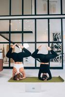 Two young woman working out indoors, doing yoga exercise on mat photo