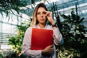 Young agricultural engineer working in greenhouse. Young female scientist looking at the camera photo