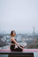 Woman practicing yoga on the mat on the roof and doing yoga exercises photo