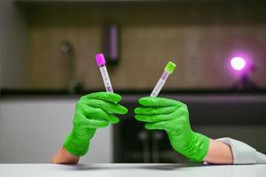 Hands in rubber gloves holds two test tube with coronavirus photo