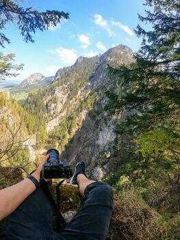 A photographer observes with his camera in hand from the top of a mountain. photo