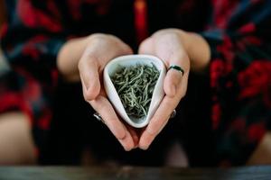 mujer joven sosteniendo un pequeño tazón de té de hierbas verdes foto