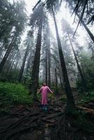 Young woman in a raincoat walks through the forest in the rain photo