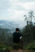 chico en la cima de una colina disfrutando de la vista de la naturaleza foto