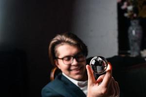 Young man holding a clear transparent crystal glass ball in their hand photo