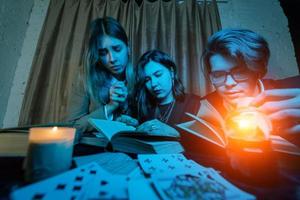 Two women and a guy are reading a mysterious books, close view photo