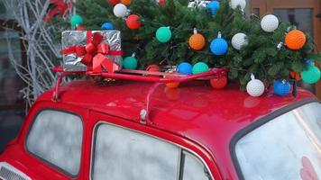 coche retro rojo con un abeto de árbol de navidad atado al techo. foto