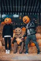 un chico y una chica con cabezas de calabaza posando en el espantapájaros foto