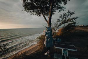 Young woman takes pictures of the sea sunset by smartphone photo