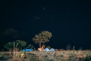 grupo de cinco viajeros descansan en la orilla del mar en el fondo del cielo nocturno. foto