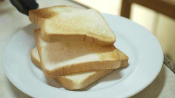 poner pan tostado fresco en un plato blanco listo para una comida saludable video