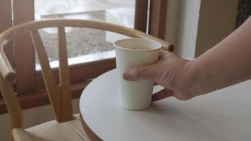 afferrare un' tazza di ghiaccio latte caffè latte macchiato su bianca tavolo, cappuccino ghiaccio caffè nel carta tazza video