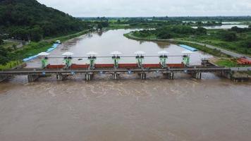 vue aérienne de l'eau libérée du canal de drainage du barrage en béton lors du débordement pendant la saison des pluies. vue de dessus de l'eau trouble de la forêt brune s'écoule d'un barrage dans le nord rural de la thaïlande. video