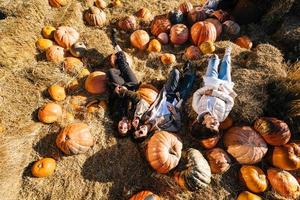 Young girls lie on haystacks among pumpkins. View from above photo