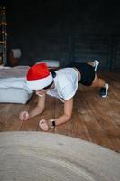 Young woman in santa hat practicing sport gymnastic exercises photo