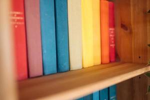 Many books on wooden shelf, close view photo