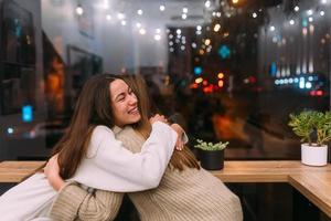 Portrait of happy cute young friends hugging each other at caffe. photo