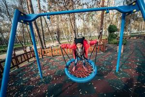 Happy child girl on swing. Little kid playing in the autumn pack. photo