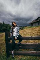 A young attractive Caucasian female sitting on a fence photo