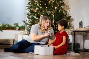 Parent and little child having fun near Christmas tree indoors. photo