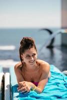 Young beautiful woman in swimsuit sunbathes on a sun lounger photo