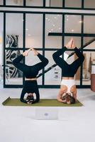 Two young woman working out indoors, doing yoga exercise on mat photo