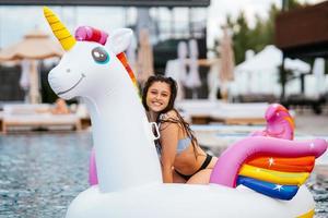 Woman on inflatable unicorn toy mattress float in pool. photo