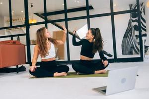 Two women while sitting in the lotus position give a high five photo