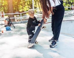 el niño pequeño lleva una patineta grande afuera foto