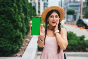 mujer que muestra un teléfono inteligente moderno con pantalla verde para reemplazo foto