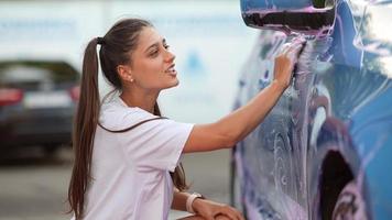 A young blonde woman washes her car photo