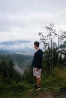 chico en la cima de una colina disfrutando de la vista de la naturaleza foto