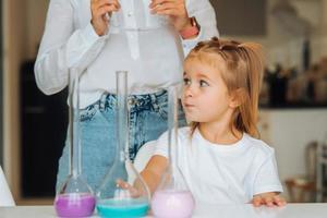 Young woman and little girl mix flasks indoors photo