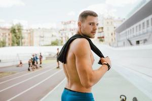 Young muscular guy with a naked torso looking back over his shoulder. photo