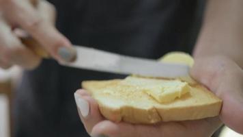 gros plan vidéo étaler du beurre frais sur le pain tranché grillé pour le petit-déjeuner repas sain. video