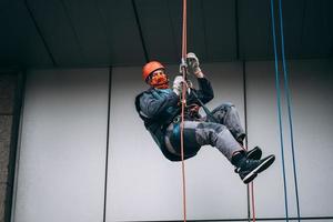 Industrial climber in uniform and helmet rises photo