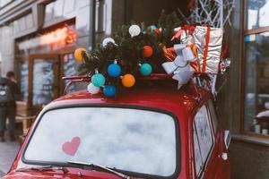 Red retro car with a Christmas tree fir tied to the roof. photo