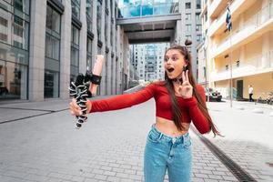 Young female blogger with smartphone streaming on the street. photo