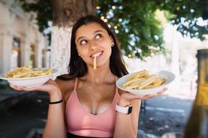 Young women hold french fries on white plates. Street cafe photo