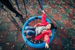 Happy child girl on swing. Little kid playing in the autumn pack. photo