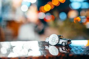 Silver bitcoin and Moskvich 401 on the table, glowing background photo