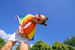 A young woman develops a rainbow flag against the sky photo