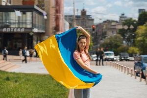 mujer joven con bandera nacional de ucrania en la calle foto