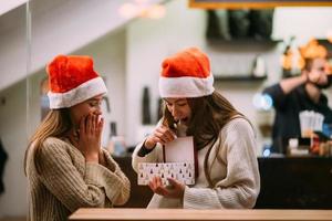 The girl gives a gift to her female friend in caffe photo